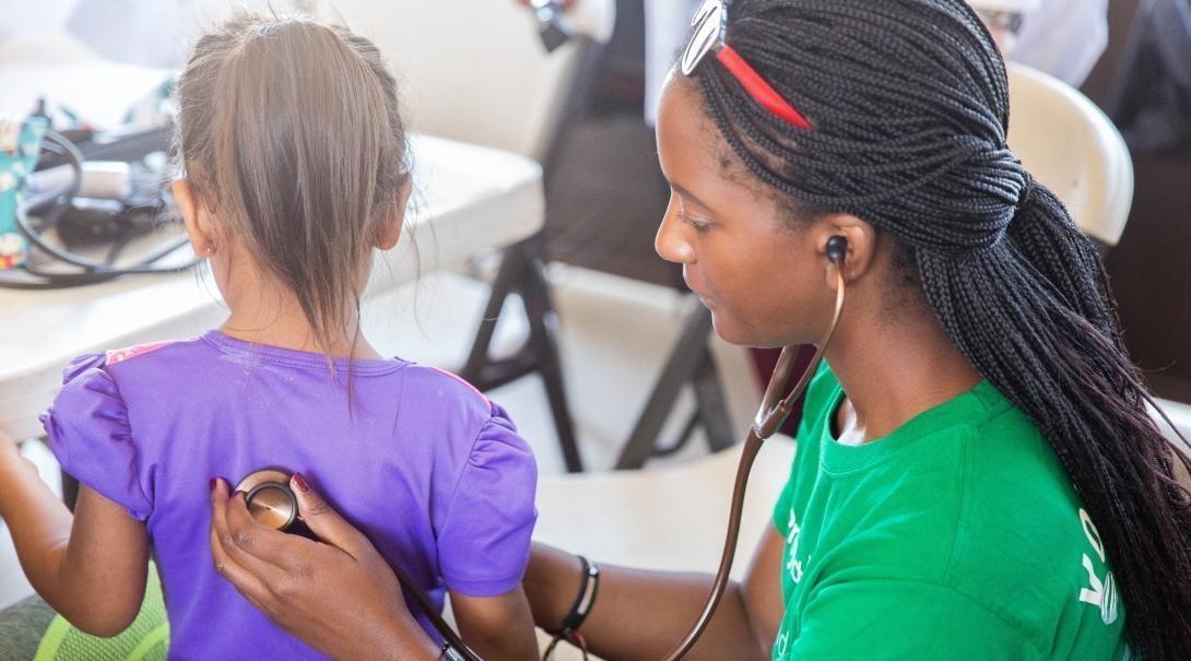 A medicine volunteer helping a small child A volunteer running medical checks on a child
